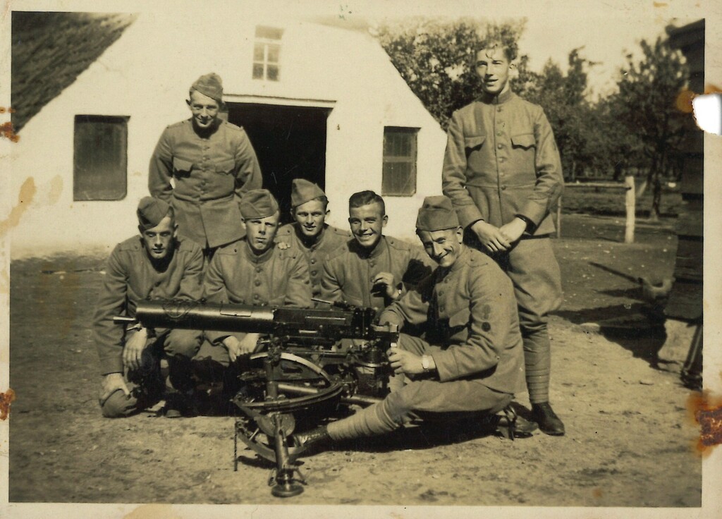 Groepsfoto achter de boerderij met mitrailleur